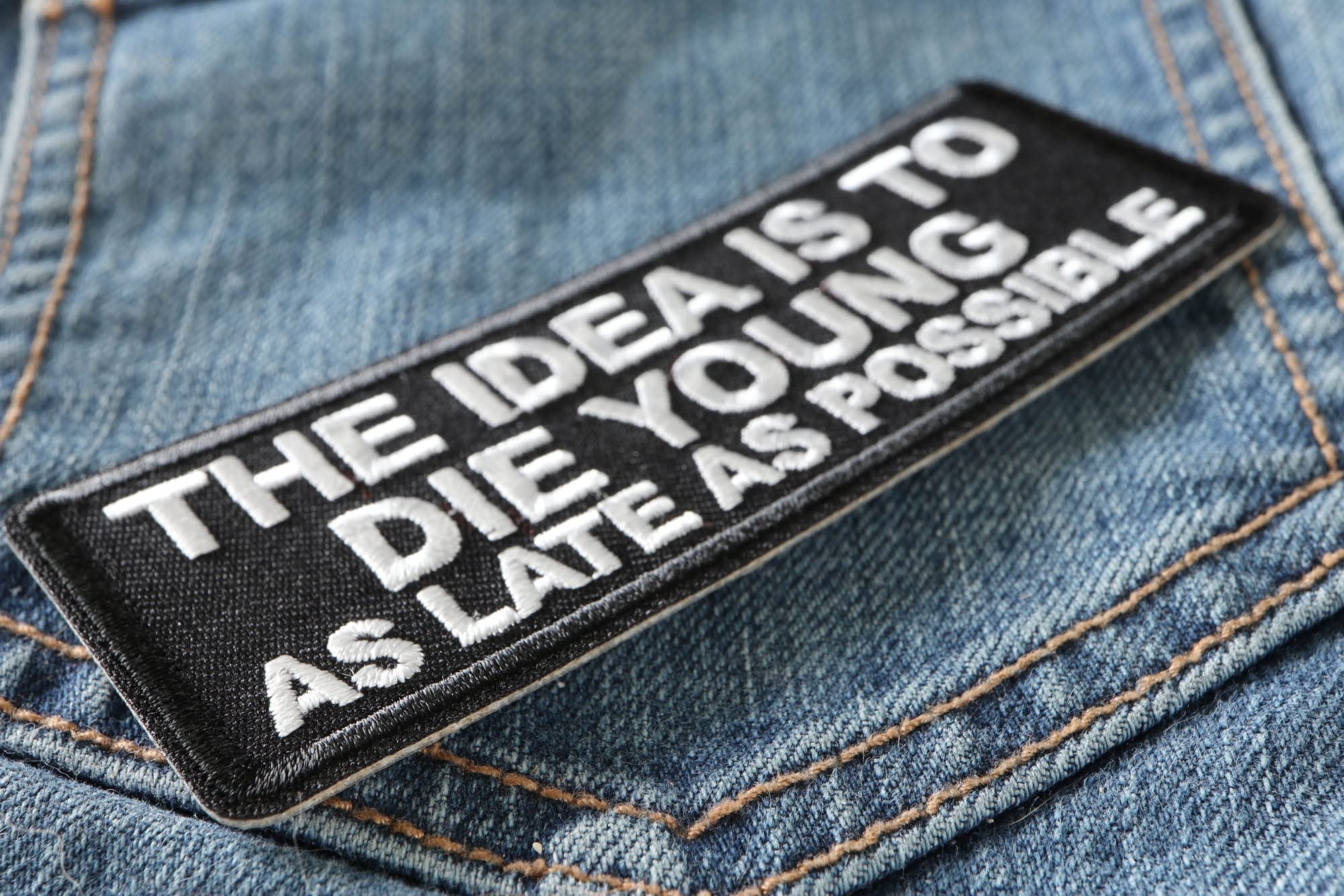 Biker Saying Patch - 'The Idea is to Die Young as Late as Possible' Iron-On Embroidered Patch for Jackets, Vests & Backpacks - Motorcycle Accessories for Bikers & Riders