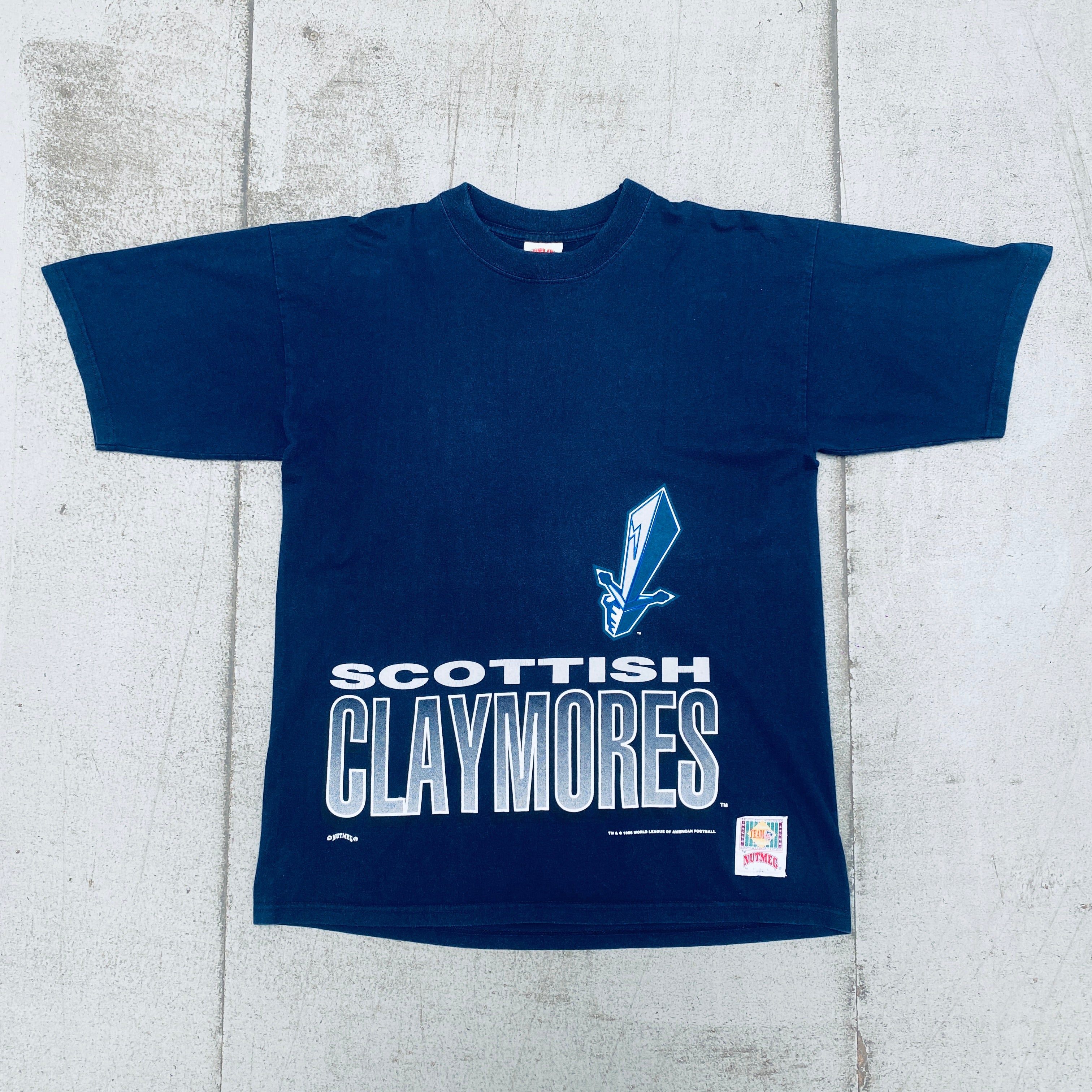 WLAF: Vintage 1996 Scottish Claymores Nutmeg Mills Graphic Spellout T-Shirt (Medium/Large) - Perfect for Football Fans, Retro Sports Apparel Collectors and 90s Nostalgia Fashion